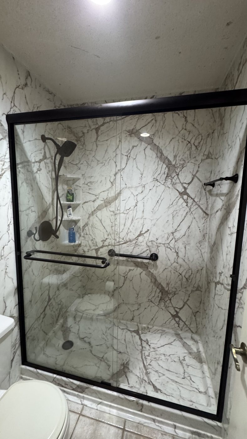 Marble-look acrylic shower with black-framed glass doors