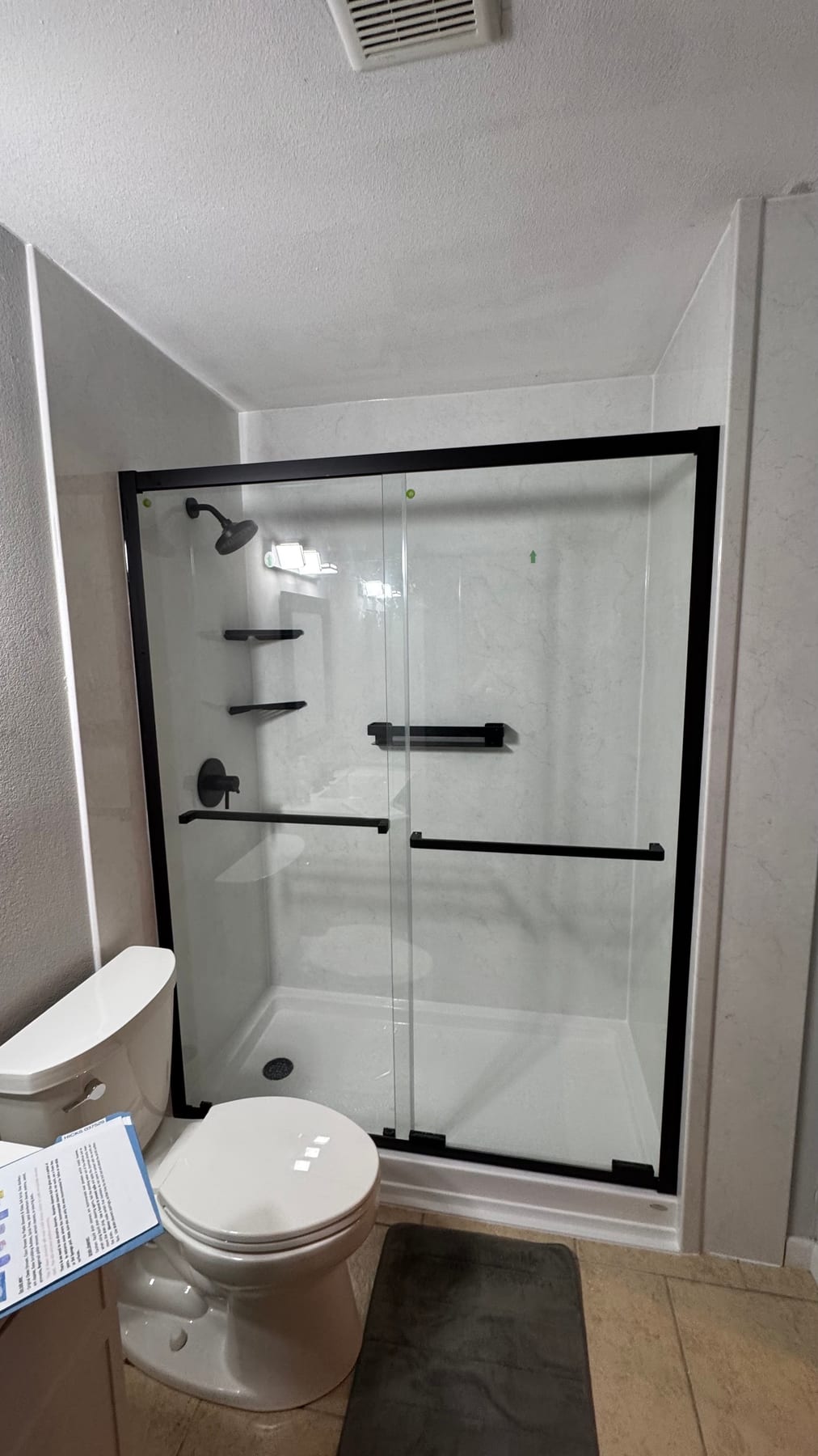 White walk-in shower with black-framed sliding glass doors
