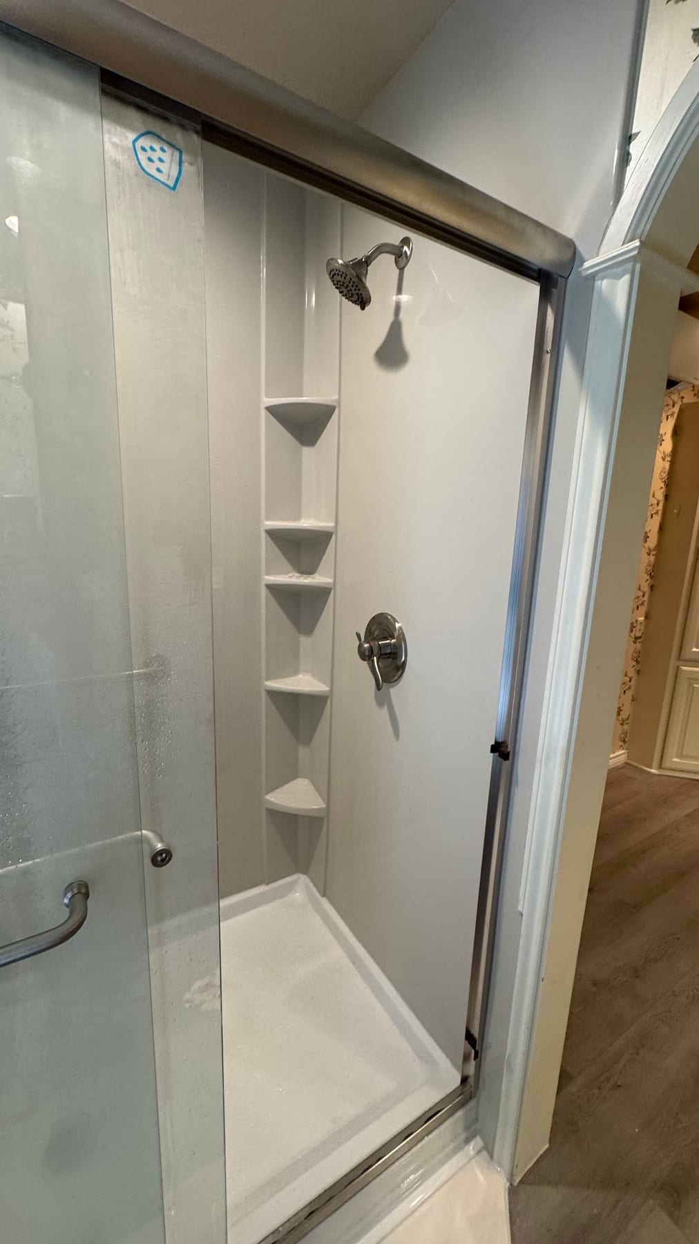 White shower with built-in corner shelves and grab bars