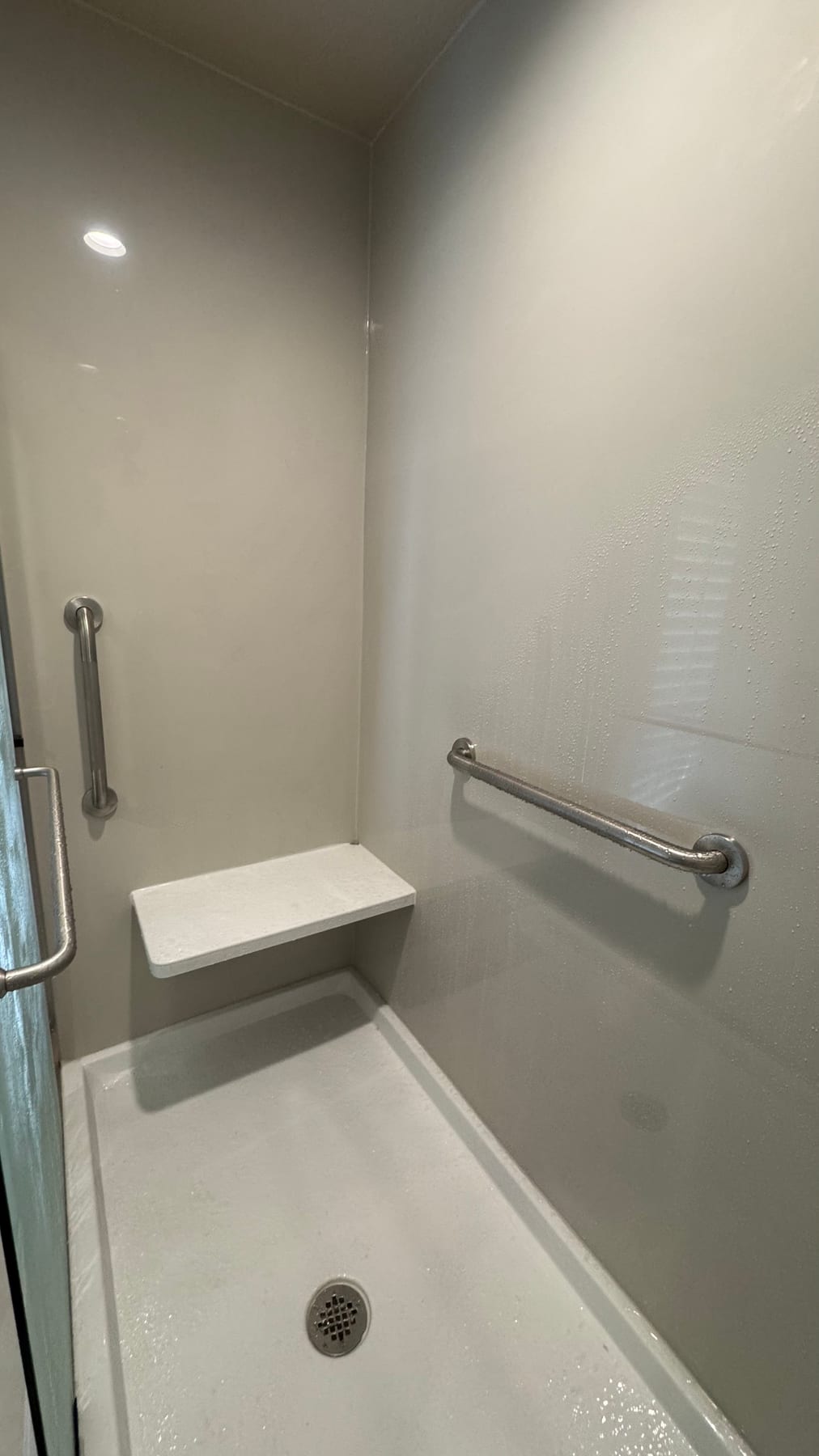 Accessible shower with fold-down seat and safety grab bars